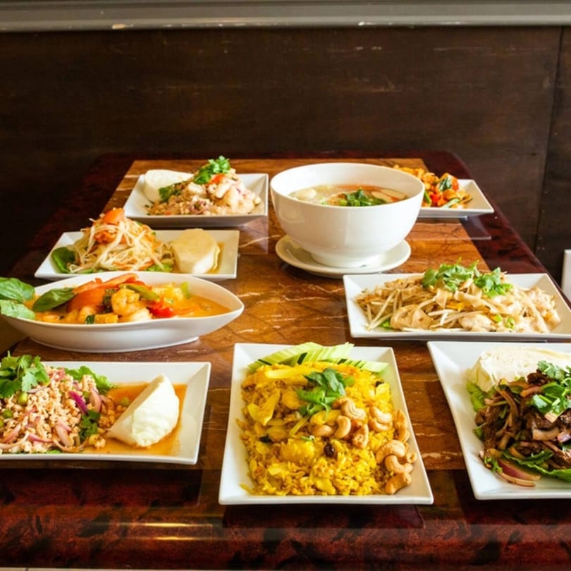 A table filled with various Thai dishes, including curries, noodles, and rice, from Thai Kitchen.